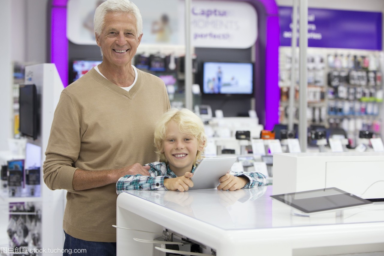 在电子产品商店里,微笑的祖父和孙子的肖像